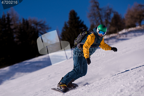 Image of snowboarder running down the slope and ride free style