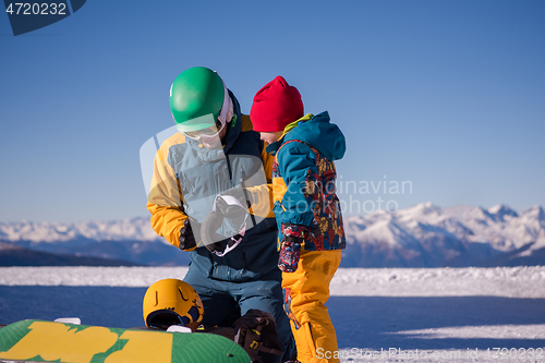 Image of father preparing his little son for the first time on a snowboar