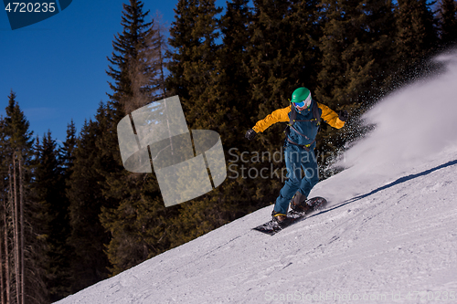 Image of snowboarder running down the slope and ride free style