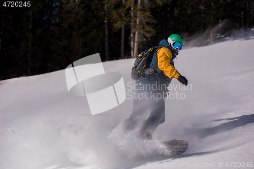 Image of snowboarder running down the slope and ride free style