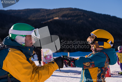 Image of father preparing his little son for the first time on a snowboar