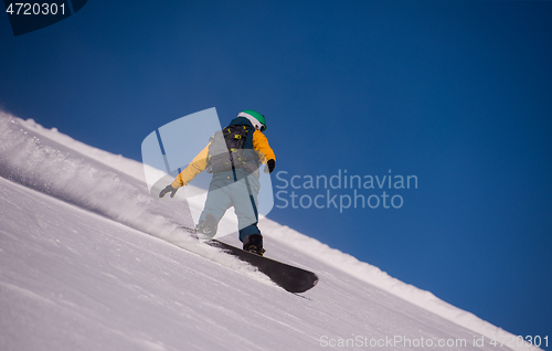 Image of snowboarder running down the slope and ride free style