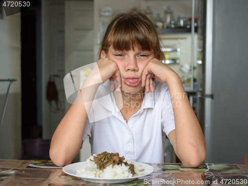 Image of The girl refuses the food offered and shows her tongue