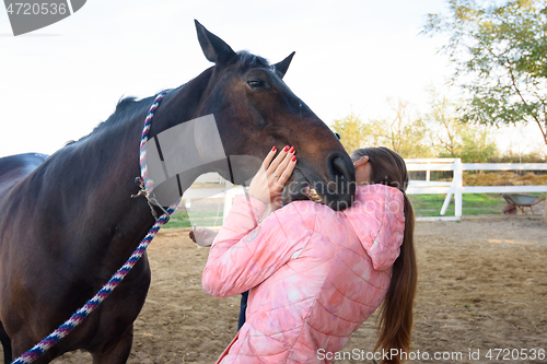 Image of The horse tries to bite the girl on the shoulder