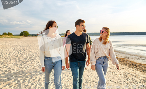 Image of happy friends walking along summer beach