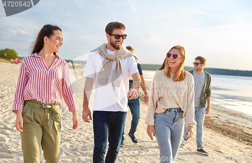 Image of happy friends walking along summer beach