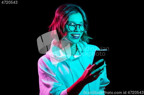 Image of woman wearing hoodie in neon lights over black