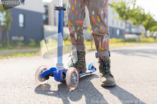 Image of close up of little boy with scooter on road