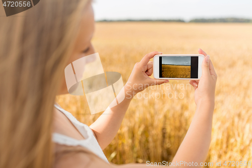 Image of girl taking picture by smartphone on cereal field