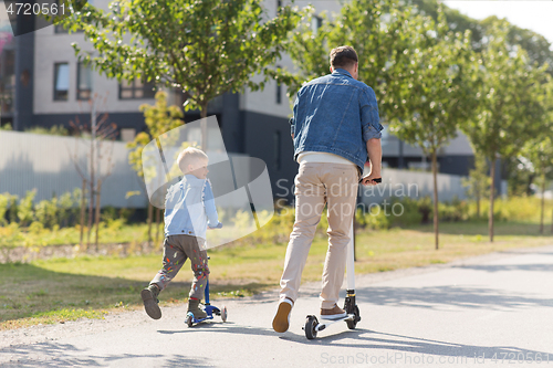 Image of happy father and little son riding scooter in city