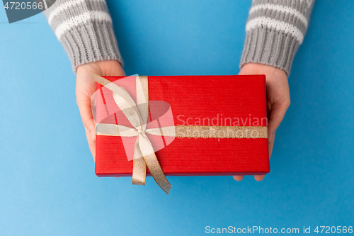 Image of hands holding red christmas gift box