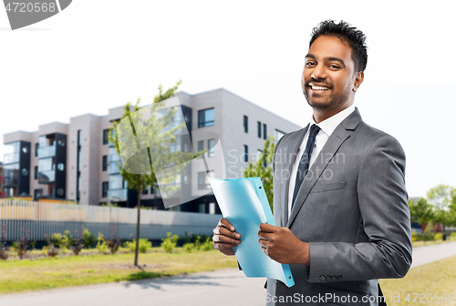 Image of indian man realtor with folder on city street