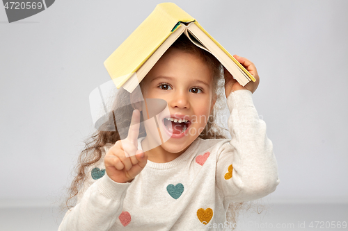 Image of portrait of smiling girl with book on head