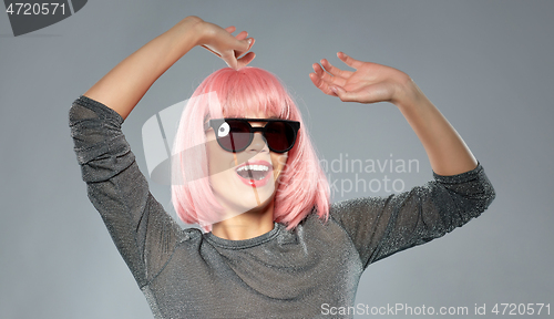 Image of happy woman in pink wig and sunglasses dancing