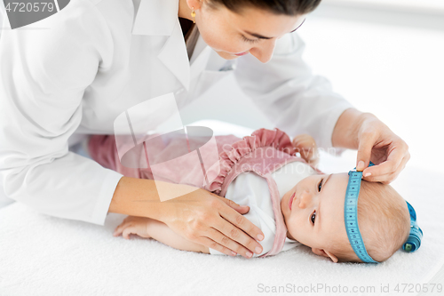 Image of pediatrician doctor measuring bab\'s head at clinic