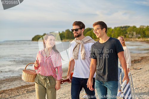 Image of happy friends walking along summer beach