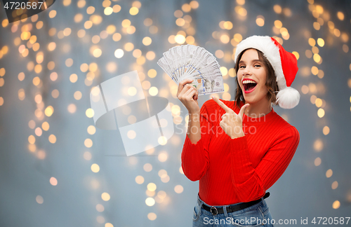 Image of happy woman in santa hat with money on christmas