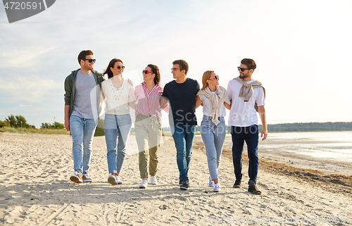 Image of happy friends walking along summer beach