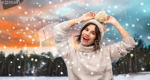 Image of woman in hat and sweater over winter forest