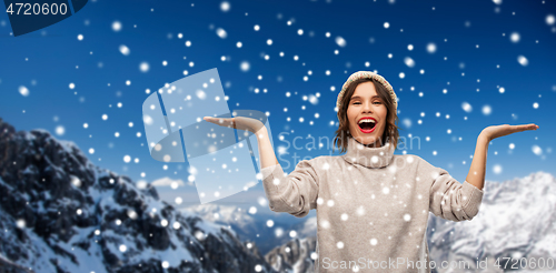 Image of young woman in knitted winter hat in mountains