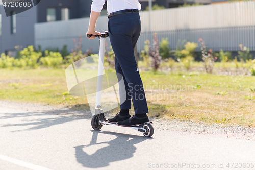 Image of young businessman riding electric scooter outdoors