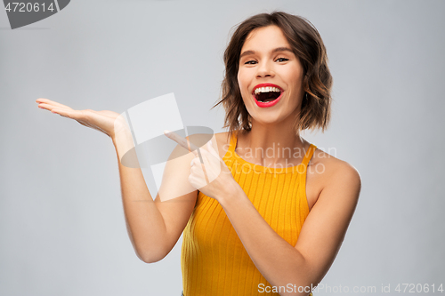 Image of happy young woman holding something on empty hand