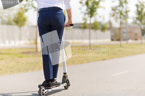 Image of young businessman riding electric scooter outdoors