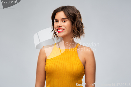 Image of happy smiling young woman in mustard yellow top