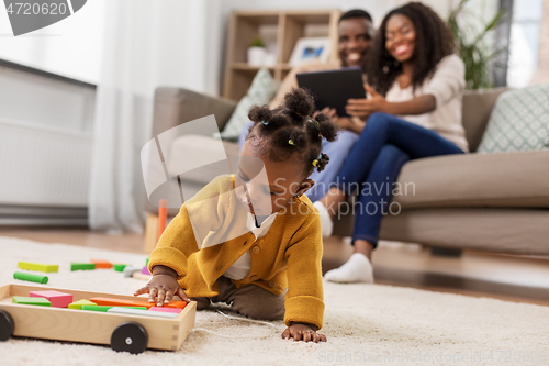 Image of african baby girl playing with toy blocks at home