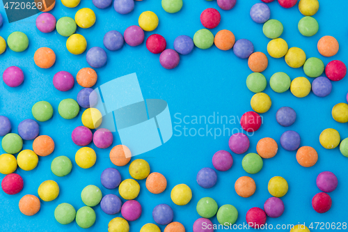 Image of candy drops in shape of heart on blue background