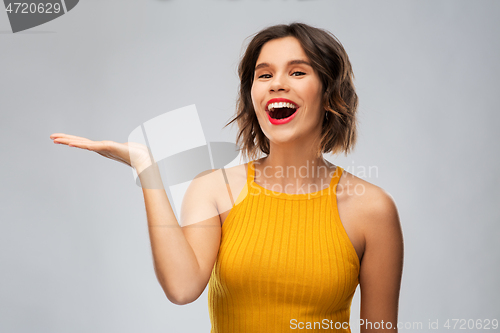 Image of happy young woman holding something on empty hand