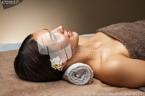 Image of young woman lying at spa or massage parlor