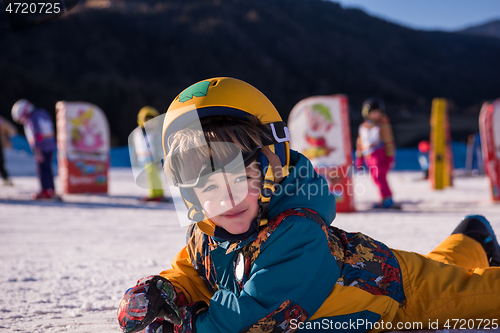 Image of little snowboarder lying on the snow