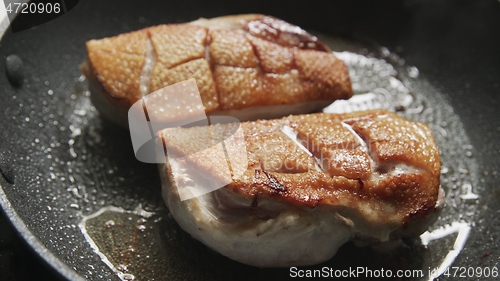 Image of Roast duck breast in frying pen closeup footage