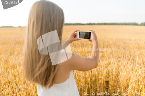 Image of girl taking picture by smartphone on cereal field