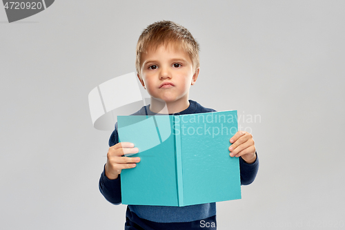 Image of displeased little boy reading book