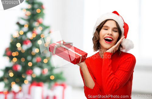 Image of happy young woman in santa hat with red gift box