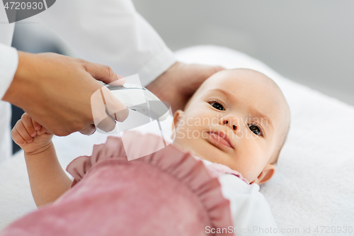 Image of doctor with thermometer measures baby temperature