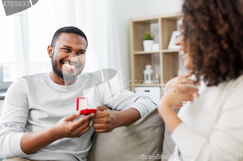 Image of african american man giving woman engagement ring