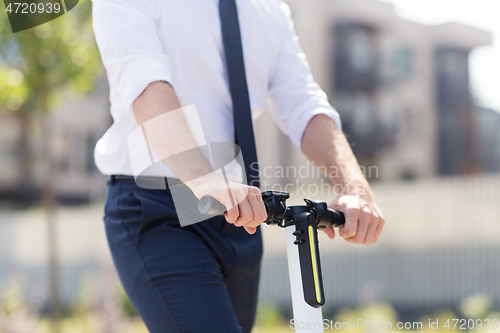 Image of young businessman riding electric scooter outdoors