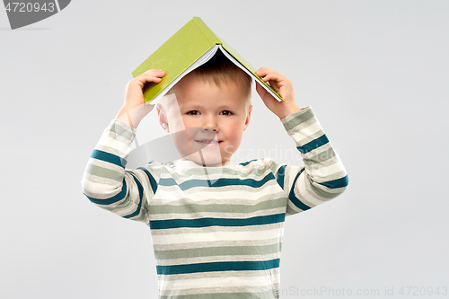 Image of portrait of smiling boy with book on head