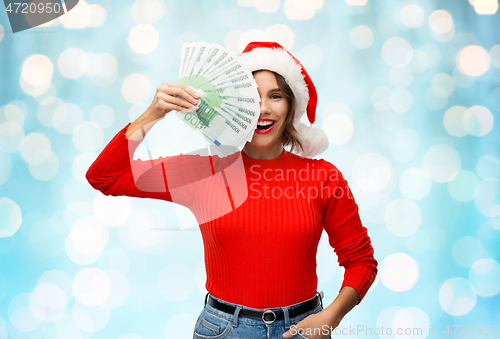 Image of happy woman in santa hat with money on christmas