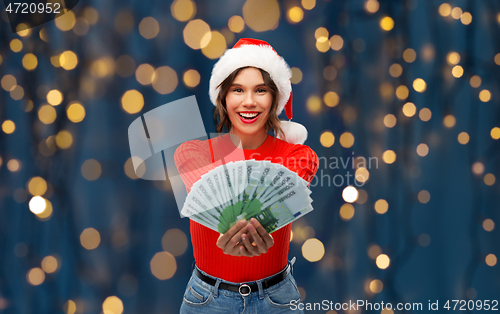 Image of happy woman in santa hat with money on christmas