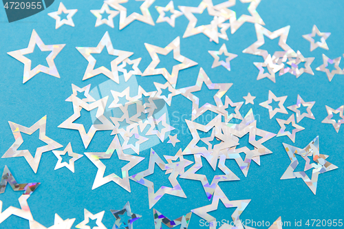 Image of star shaped confetti decoration on blue background