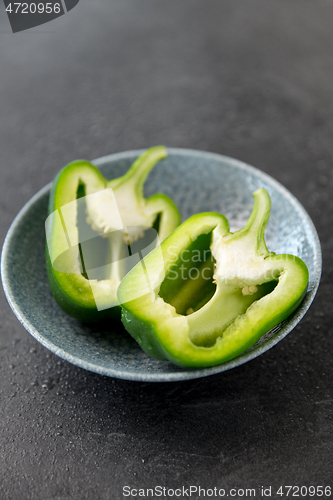 Image of cut green pepper in bowl on slate stone background