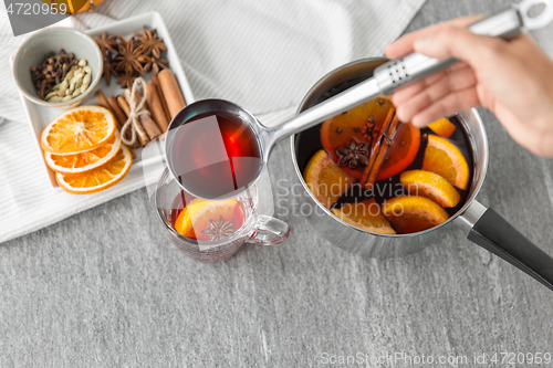 Image of hand with ladle pouring hot mulled wine to glass