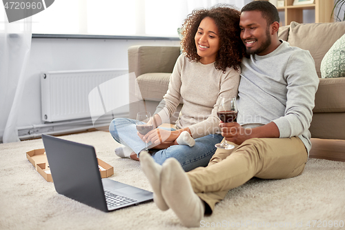 Image of happy couple with laptop drinking red wine at home