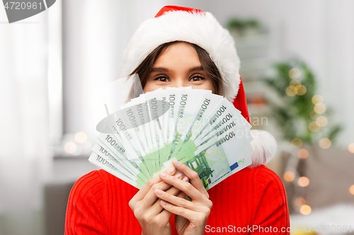 Image of happy woman in santa hat with money on christmas