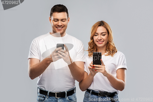 Image of happy couple in white t-shirts with smartphones