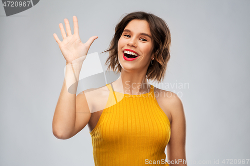 Image of happy smiling young woman waving hand